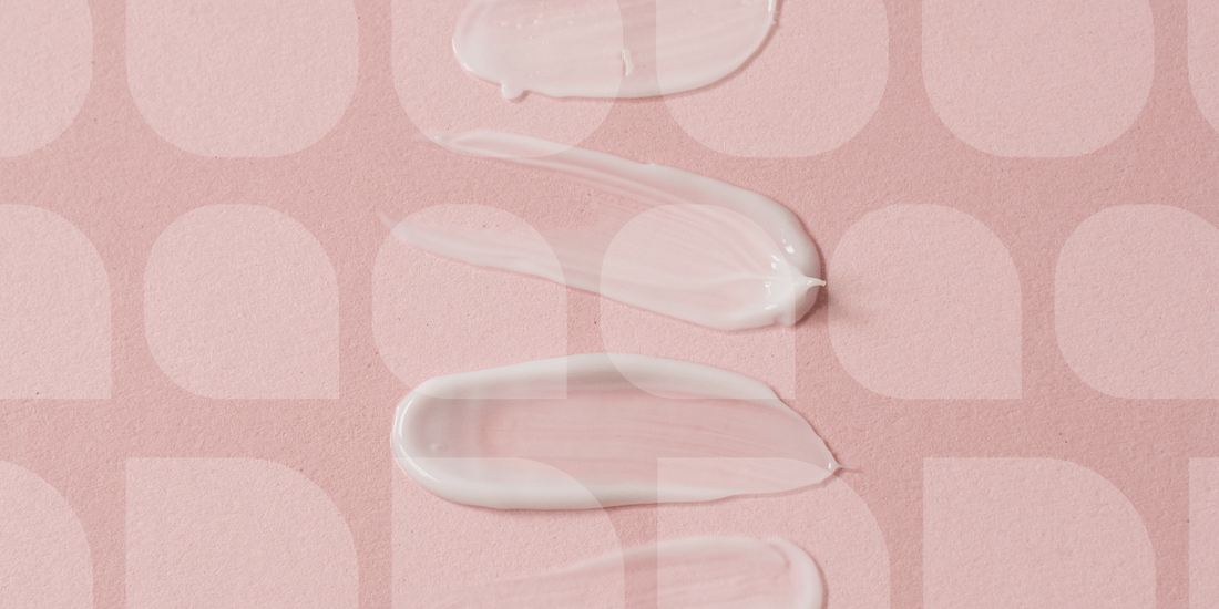 Close-up of skincare cream swatches on a soft pink background with abstract pattern droplet design.