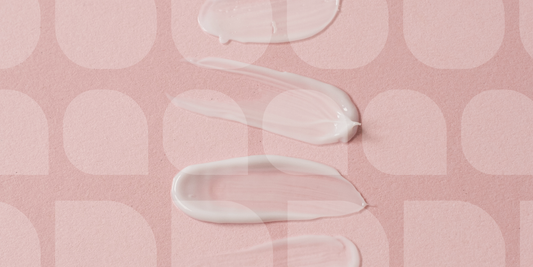 Close-up of skincare cream swatches on a soft pink background with abstract pattern droplet design.
