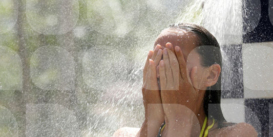 Close up of woman showering outdoors with her hands covering her face