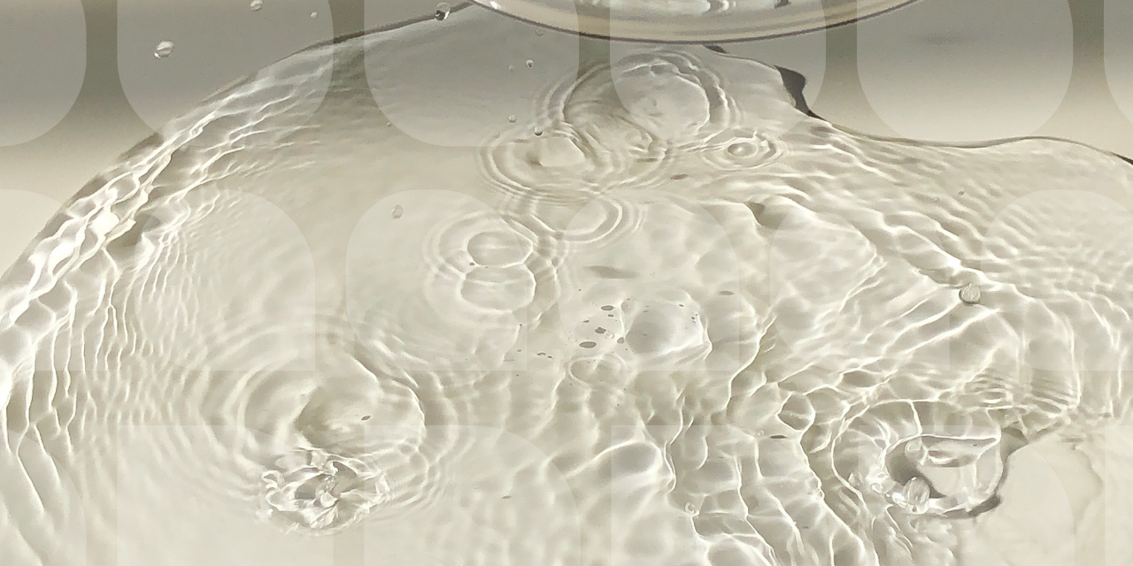 Close-up of clear water ripples and bubbles creating soft reflections on a neutral background.