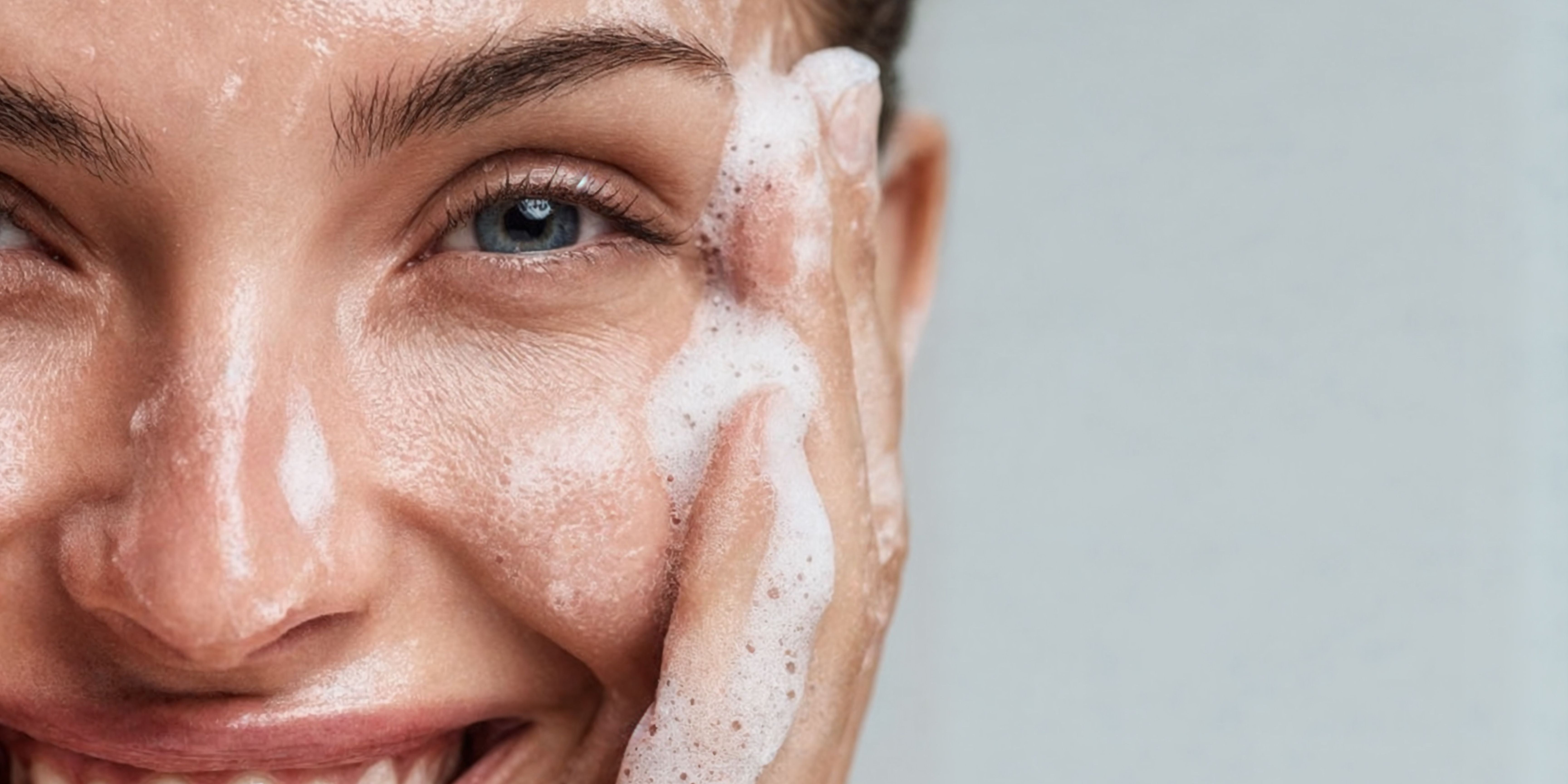 Close up image of woman washing her face with soap suds