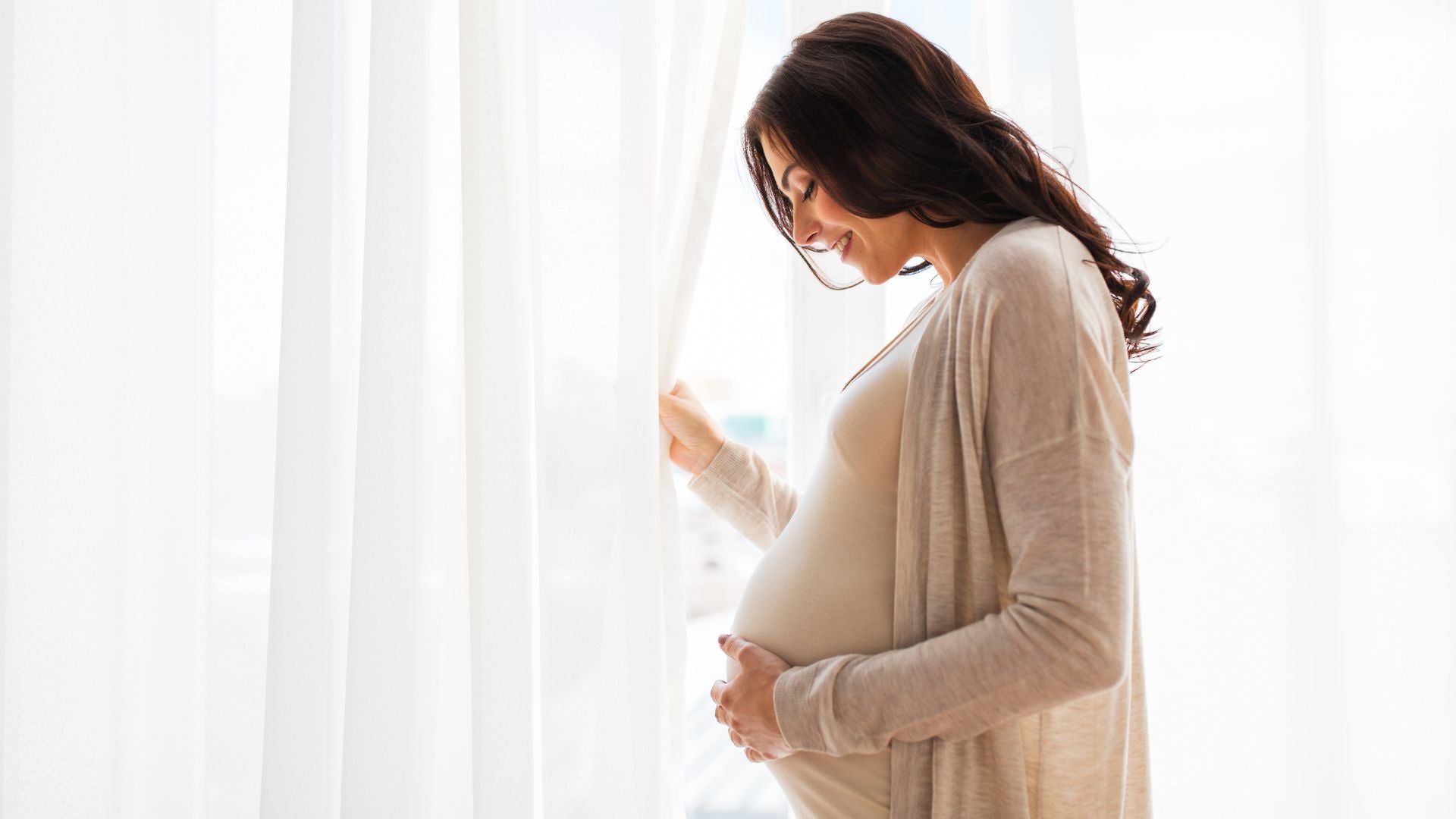 Pregnant women smilling while looking into her belly