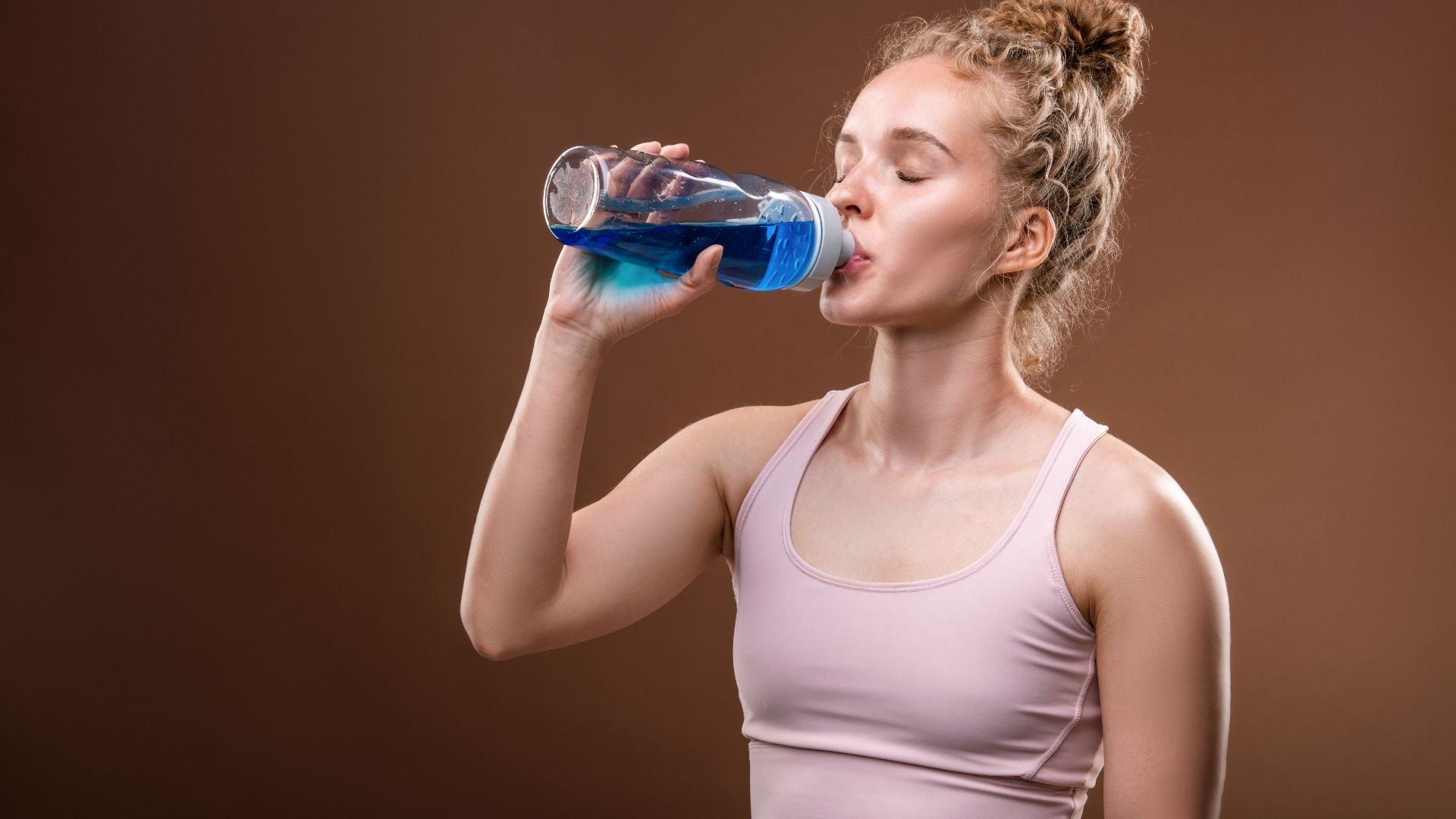 A woman drinking a hydration drink after a workout