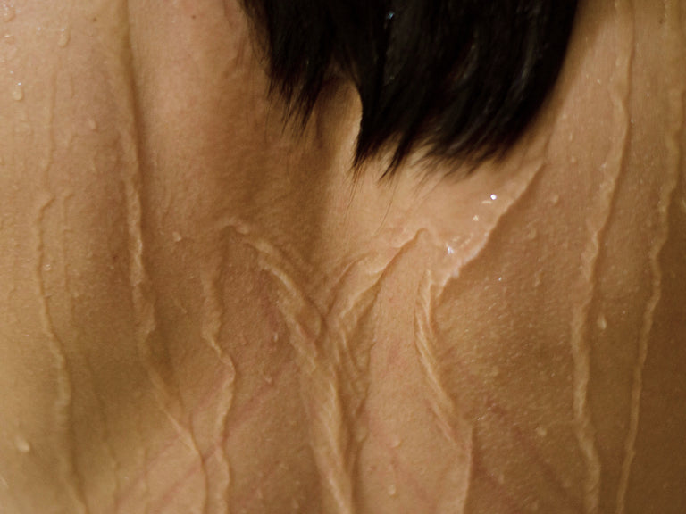 Close-up of a woman's back, with visible water streaming down