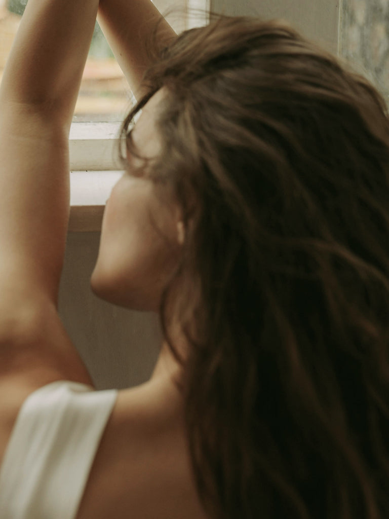 Woman with long hair looking out a window