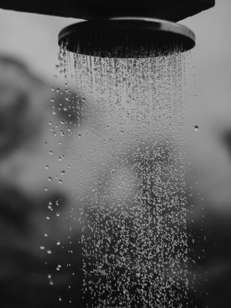 showerhead releasing water droplets against a blurred background