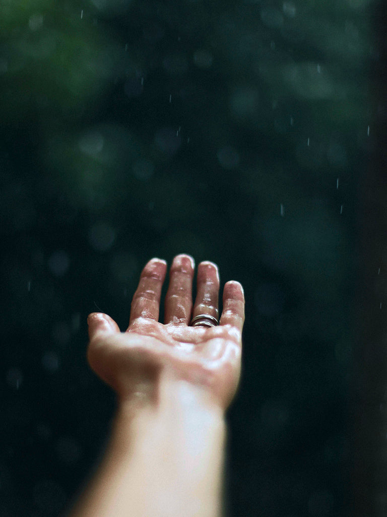 Hand with water droplets against a dark, blurred background