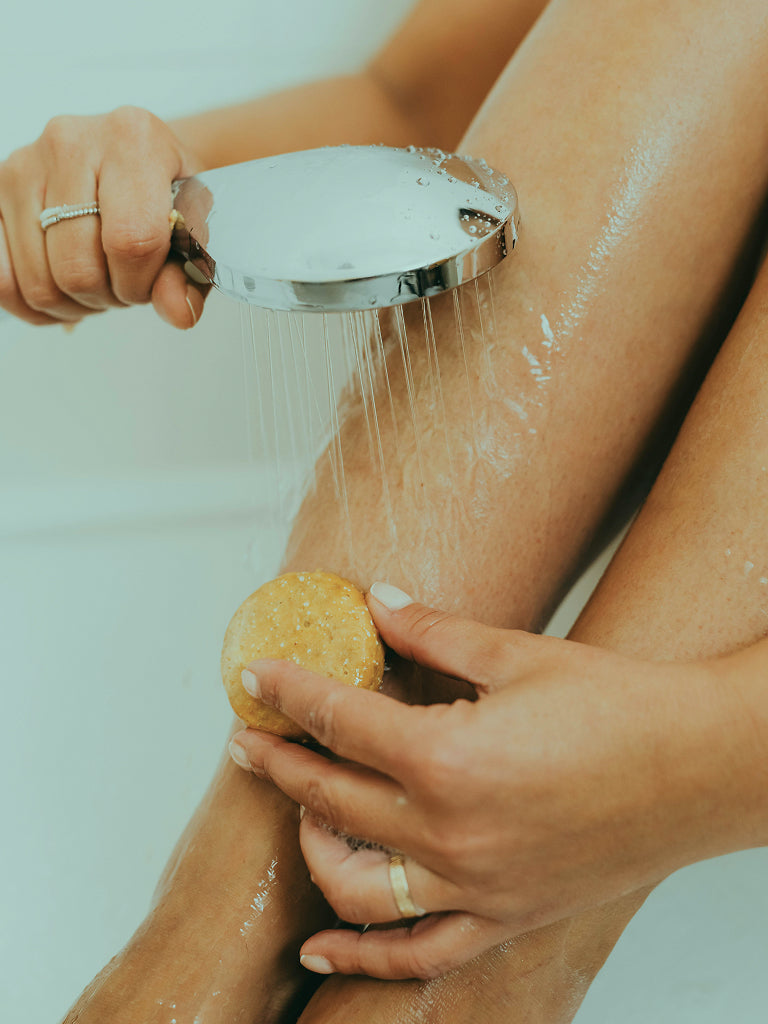 Person showering with a bar of soap on a light background