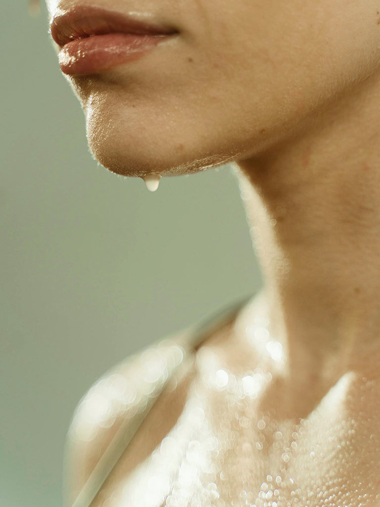 Close-up of a womans neck and shoulders dripping with water 