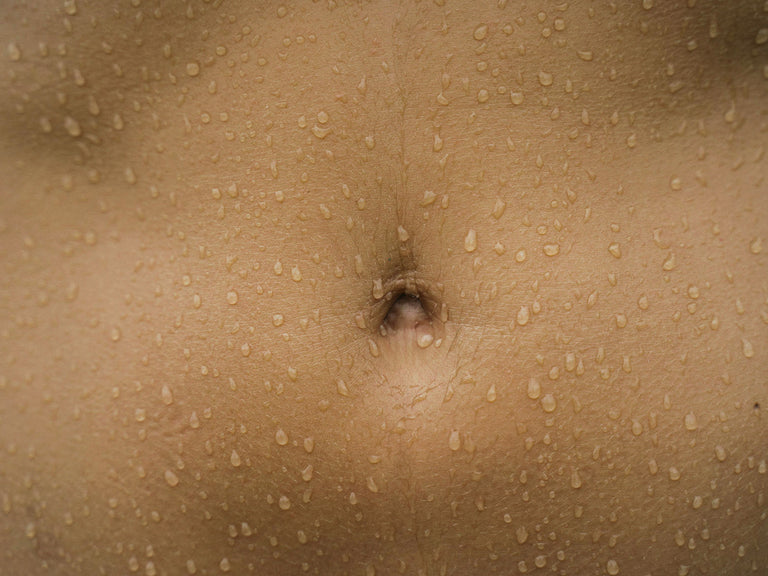 Close-up of a person's belly button water droplets visible on her skin