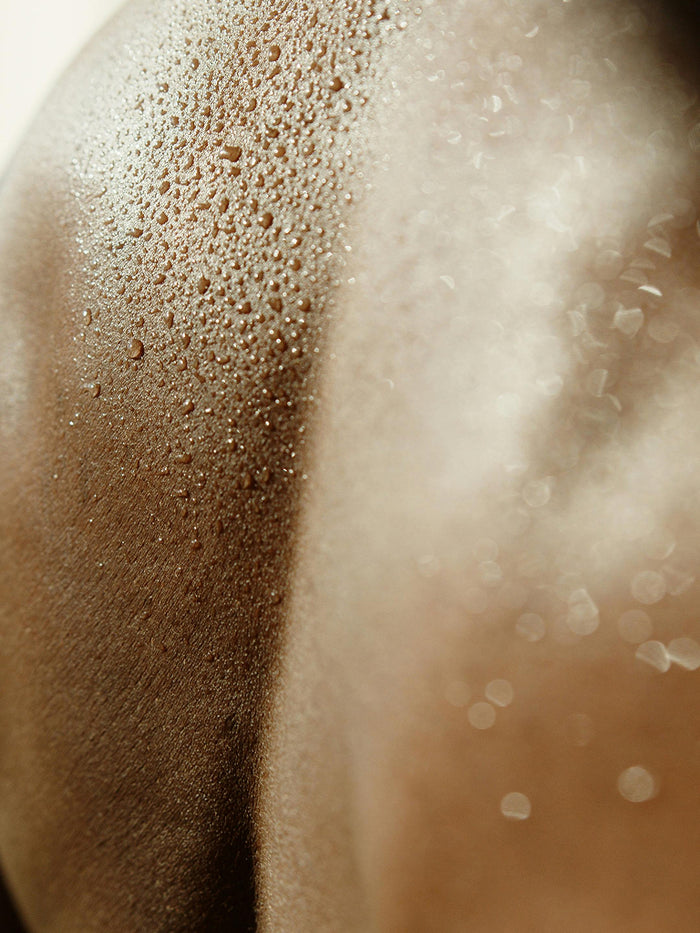 Close-up of damp skin with water beads shining in the light