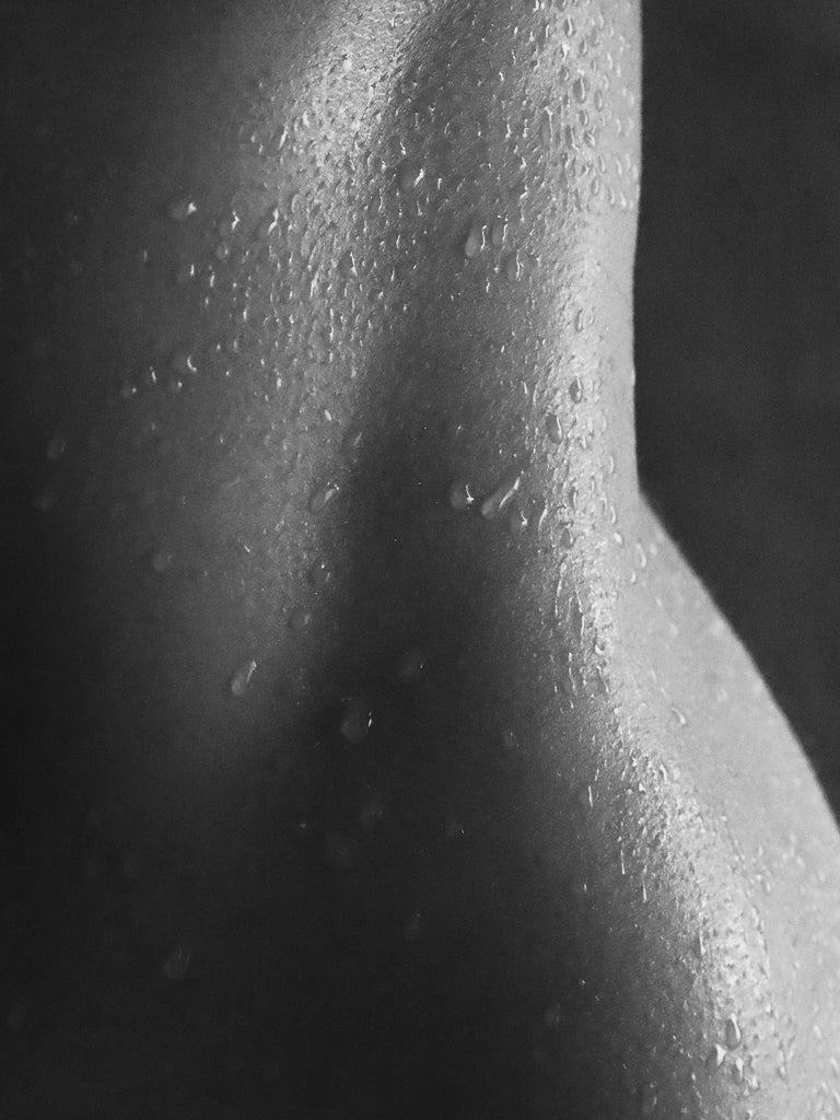 Close-up of a person's shoulder with water droplets on a dark background
