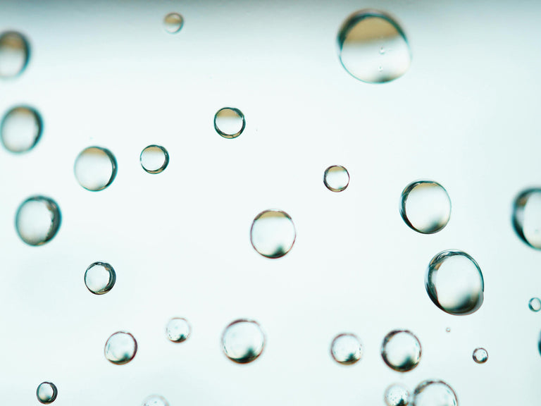 Close-up of water droplets on a glass surface with a blurred background