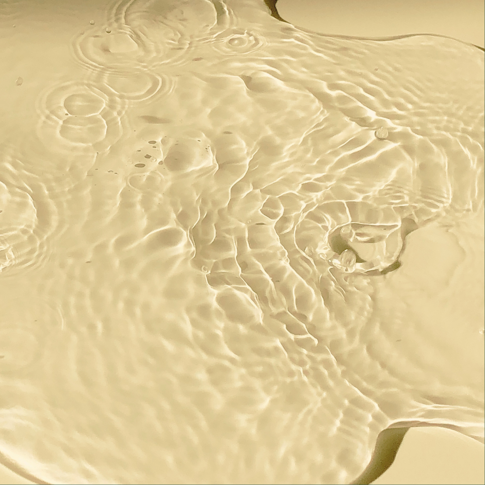 Close-up of clear water flowing over sand with ripples and reflections.